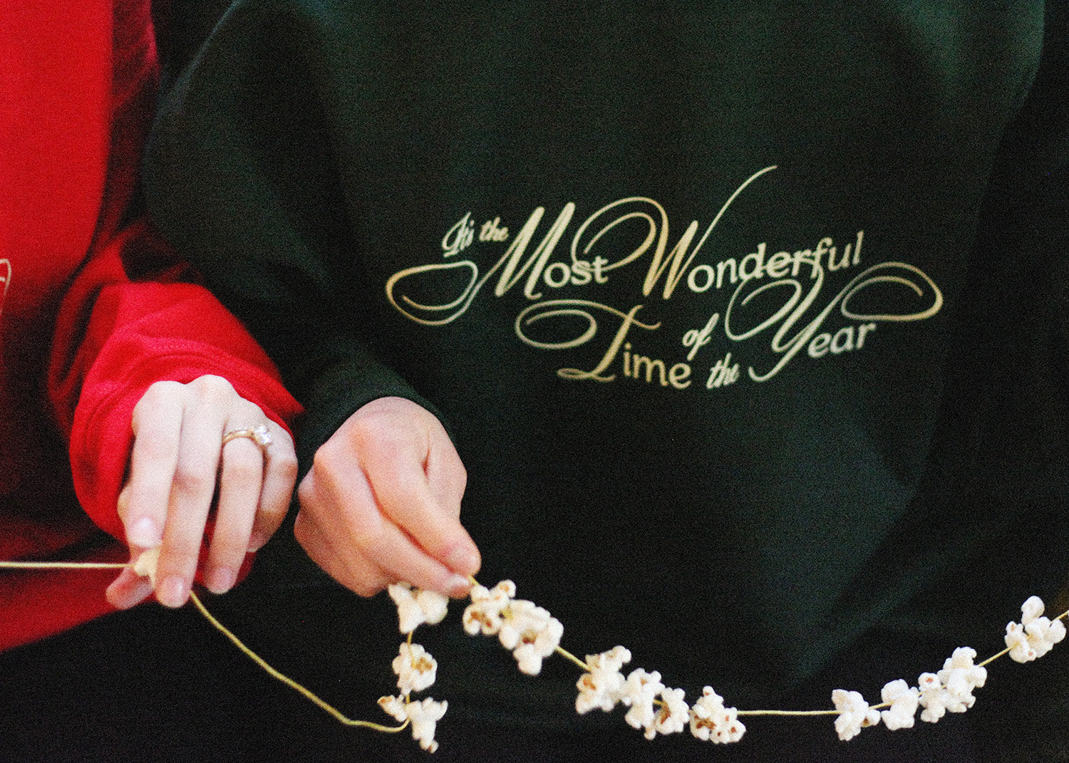 Woman in most wonderful time of the year sweatshirt stringing popcorn for Christmas tree
